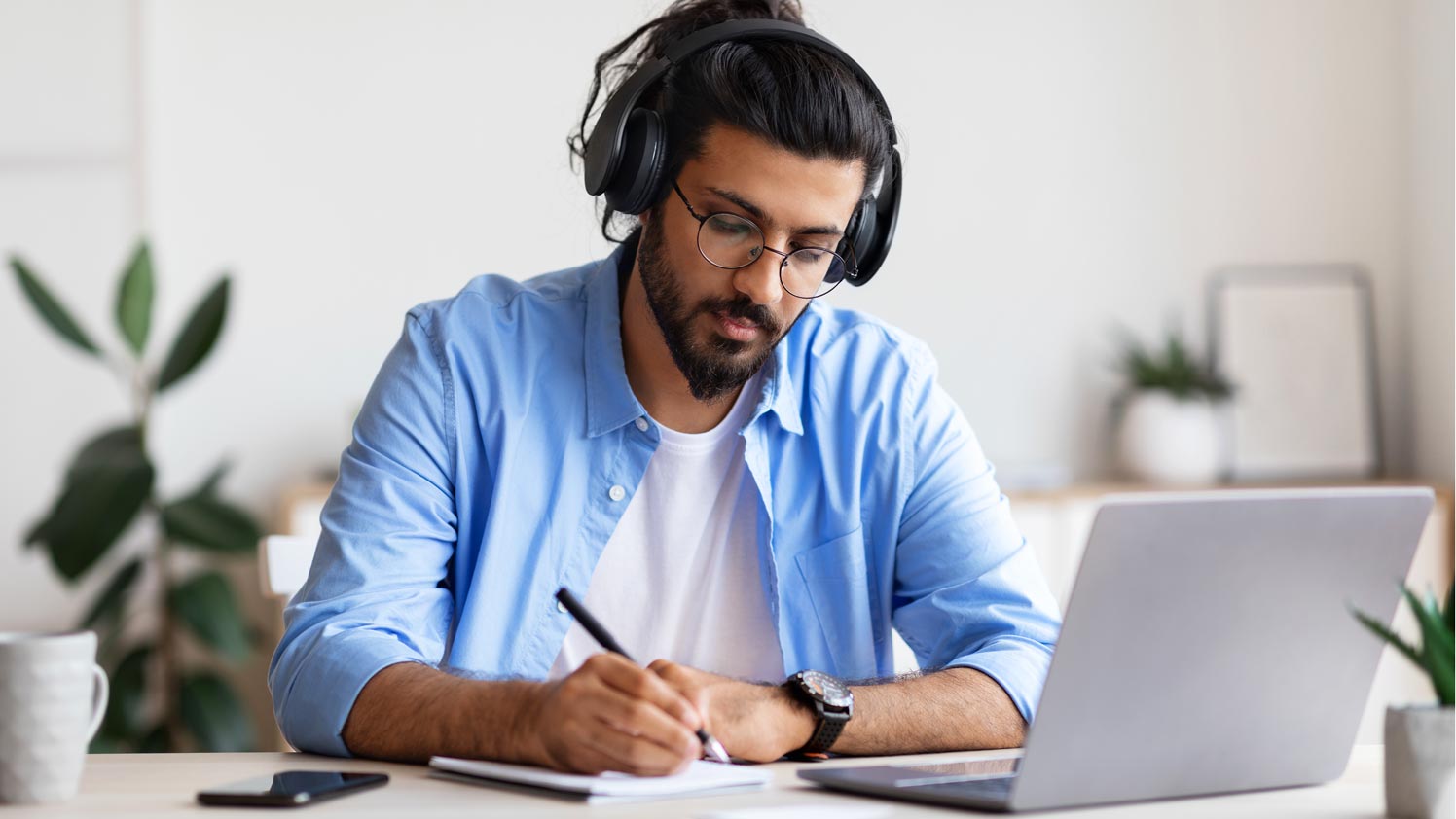 Person sitting wearing headphones and writing on paper
