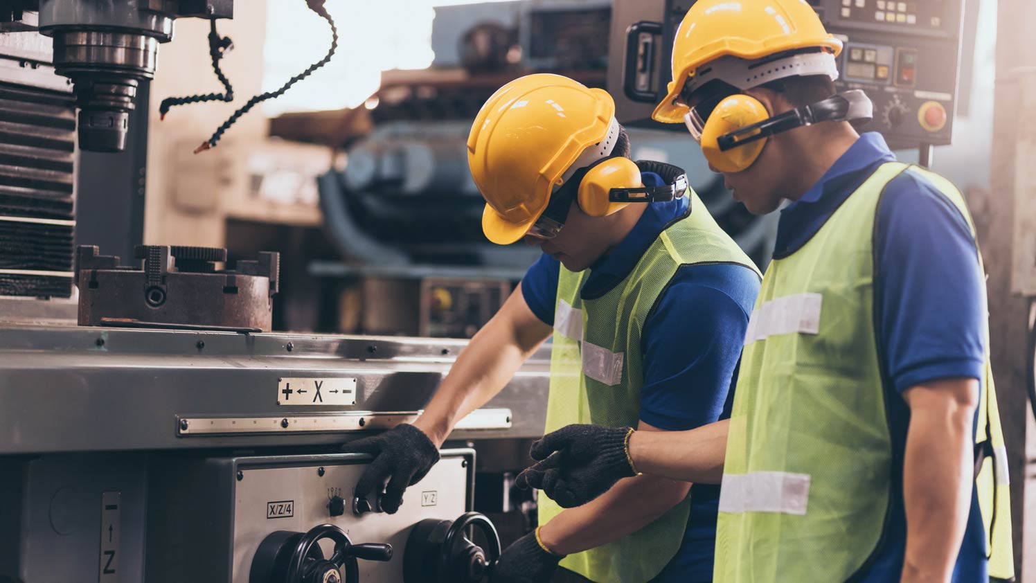 Two construction workers working on a machine