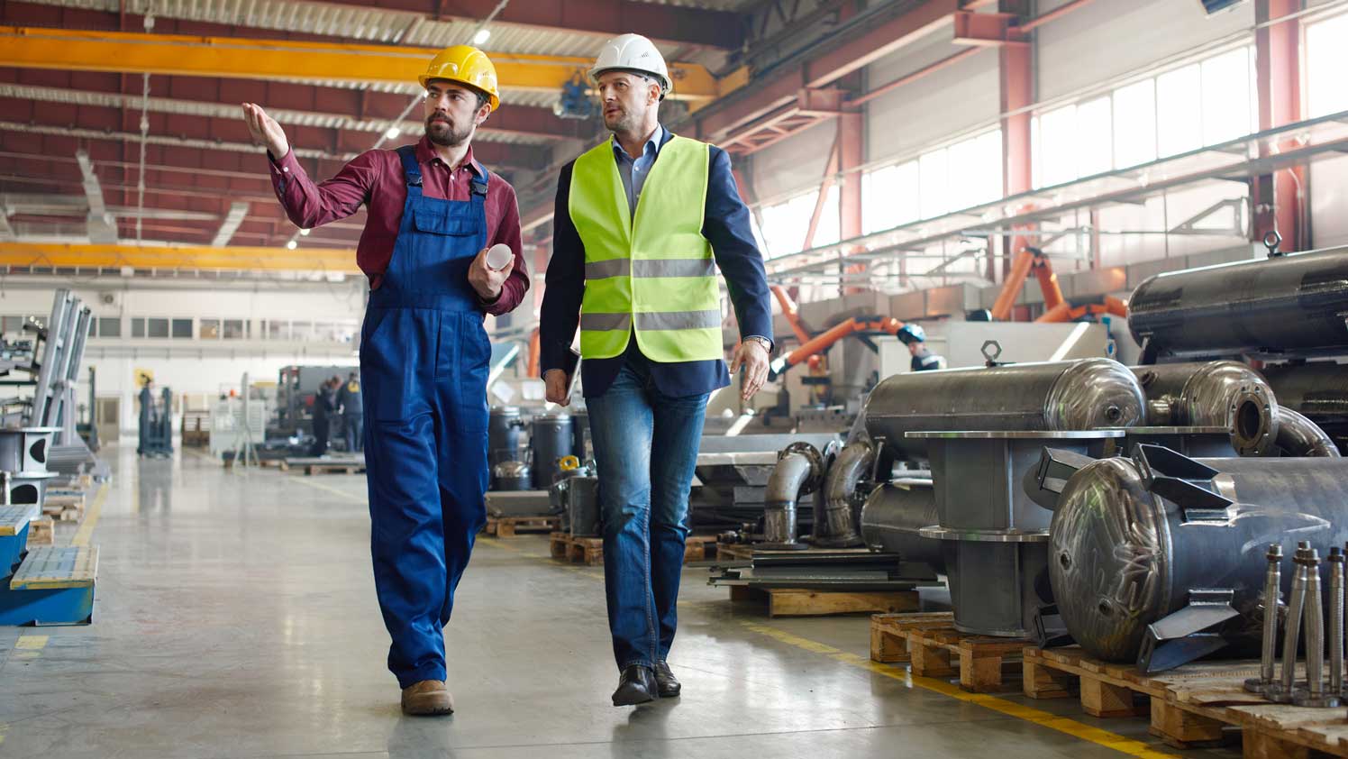 One construction worker showing another worker around a warehouse