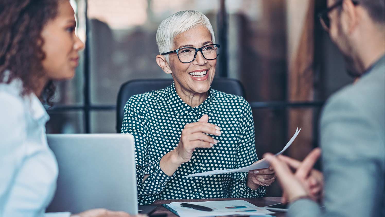 Woman smiling while handing over paper to coworker