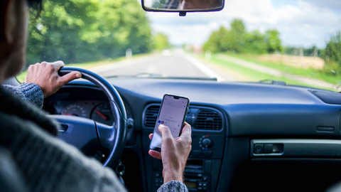 Driver looking at cell phone while driving car 