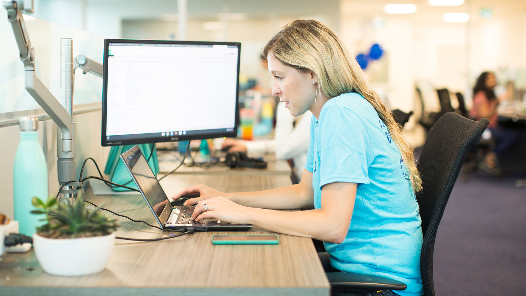 Blonde female Geotab employee working at a desk on a laptop