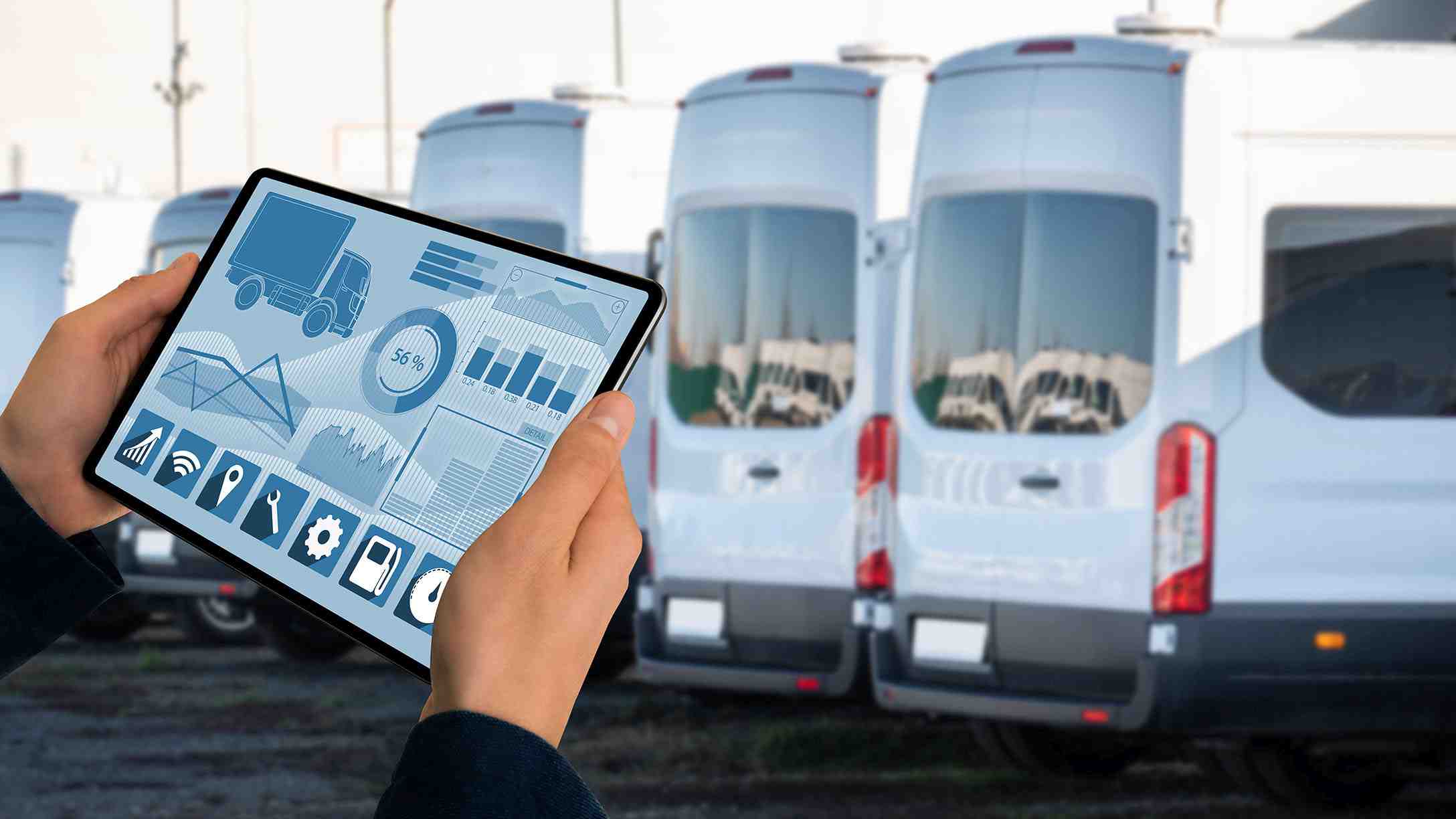 Person standing near vehicles while looking at the analytics of the vehicles on a tablet