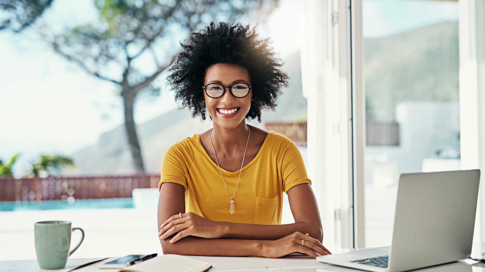 A girl with a computer and a coffee mug smiling