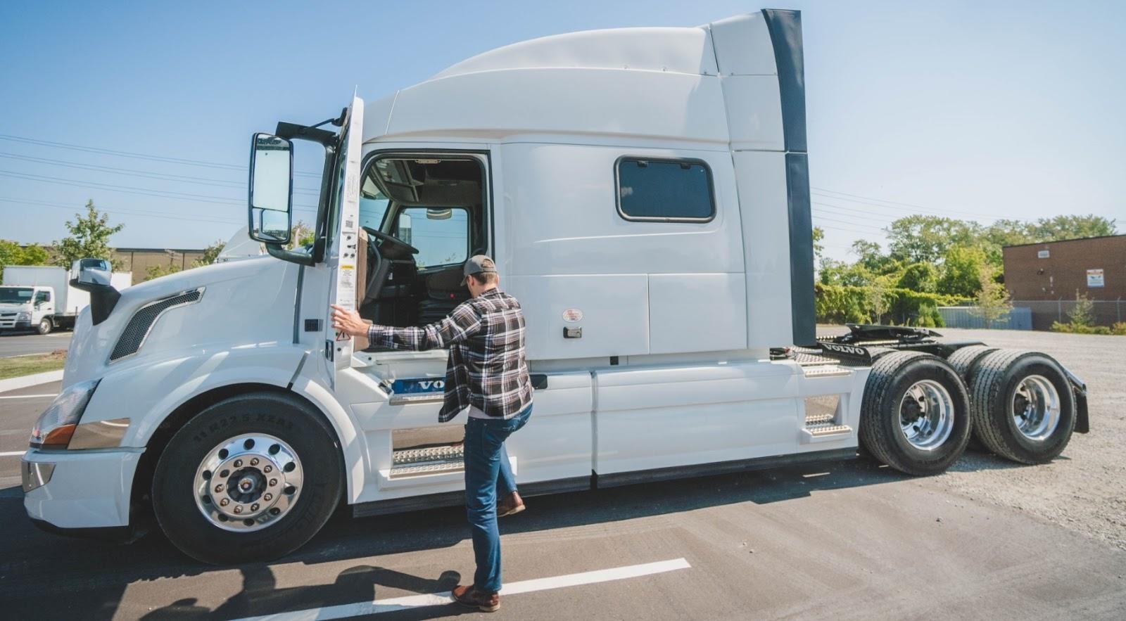 Man climbing into the driver’s seat of a truck without a trailer attached.