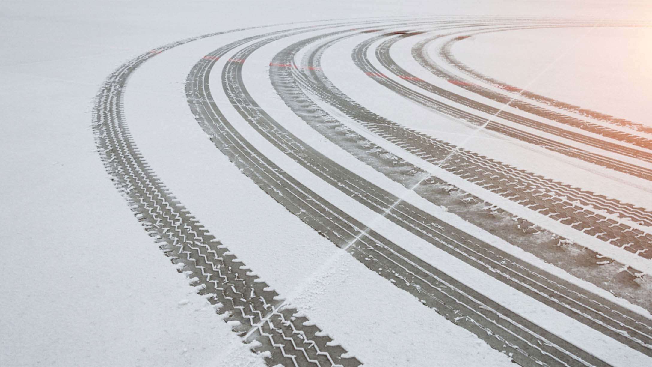 multiple sets of tire tracks in snow on a road