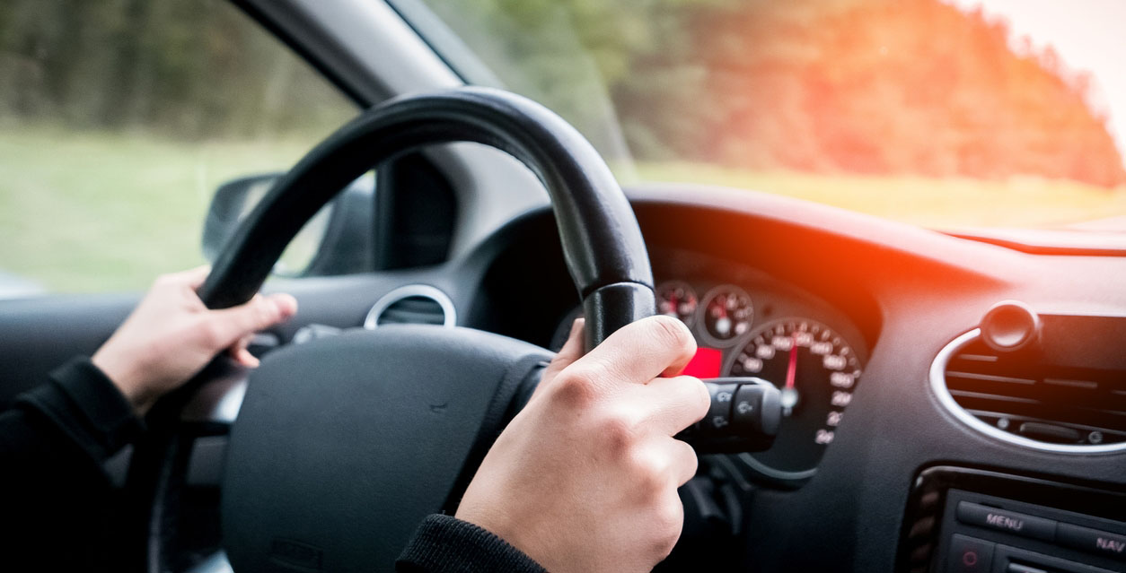 Closeup of person driving with two hands on the steering wheel