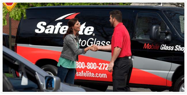 Employee wearing red shirt shaking female customers hand in front of company van.
