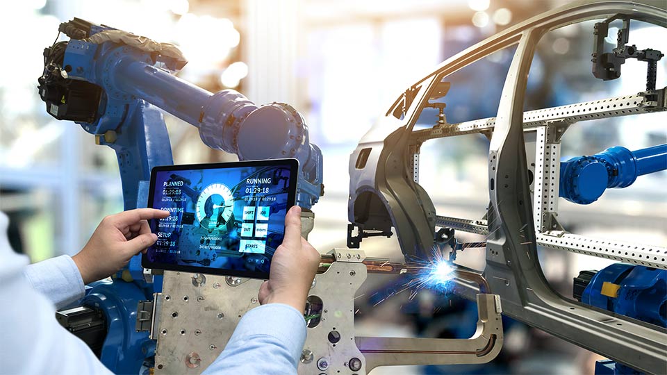 A person holding up a tablet at a car manufacturing plant