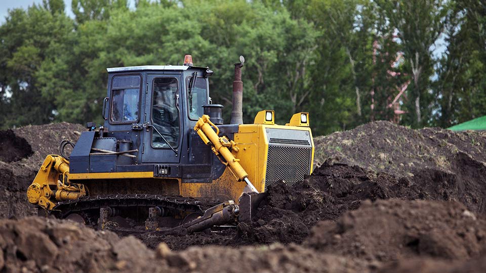 Yellow excavator digging in dirt