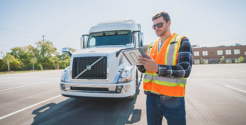 A man standing outside of a semi truck with a tablet