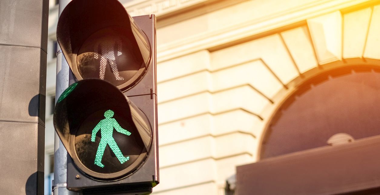 A crosswalk light with the green human walk signal flashing