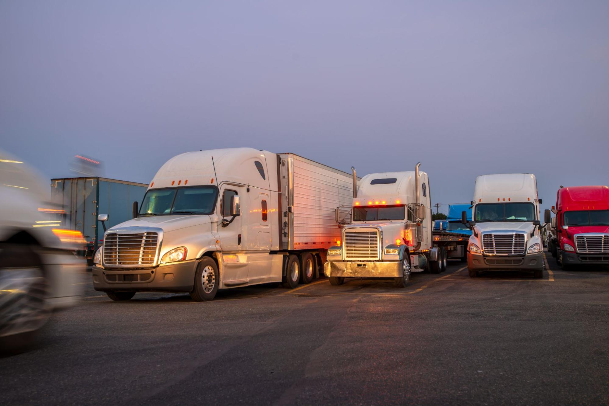 A lot of trucks with the evening sky in the background.