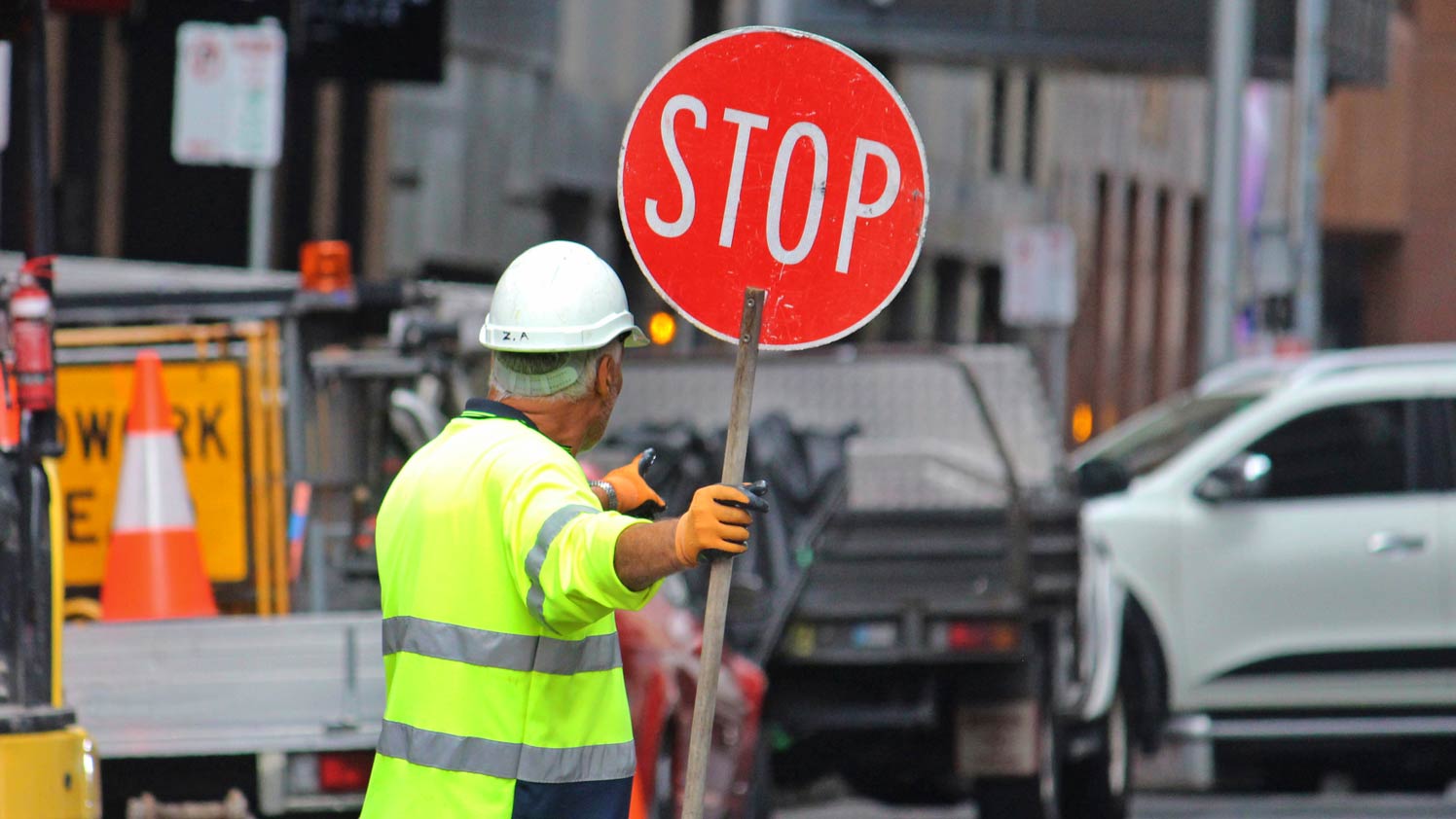Construction worker carrying stop sign on road