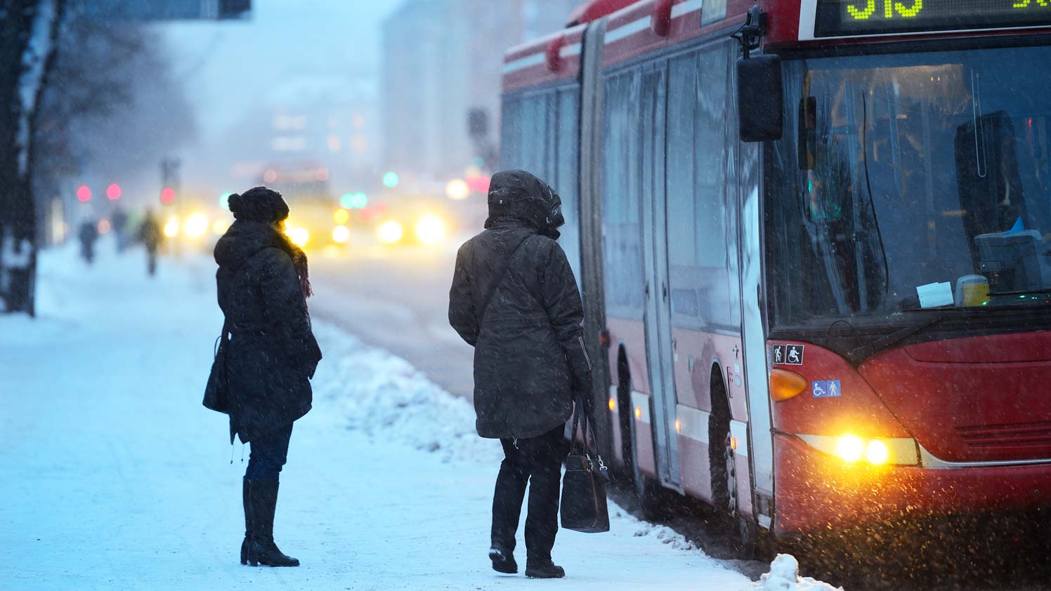 Two people waiting for the bus in the snow