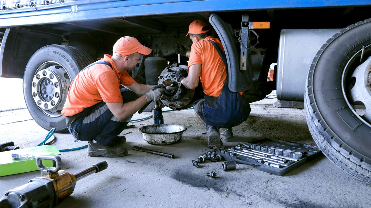 Two mechanics replacing the tire of a commercial vehicle