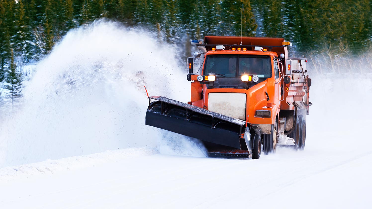 Orangefarbener Schneepflug beim Schneepflügen