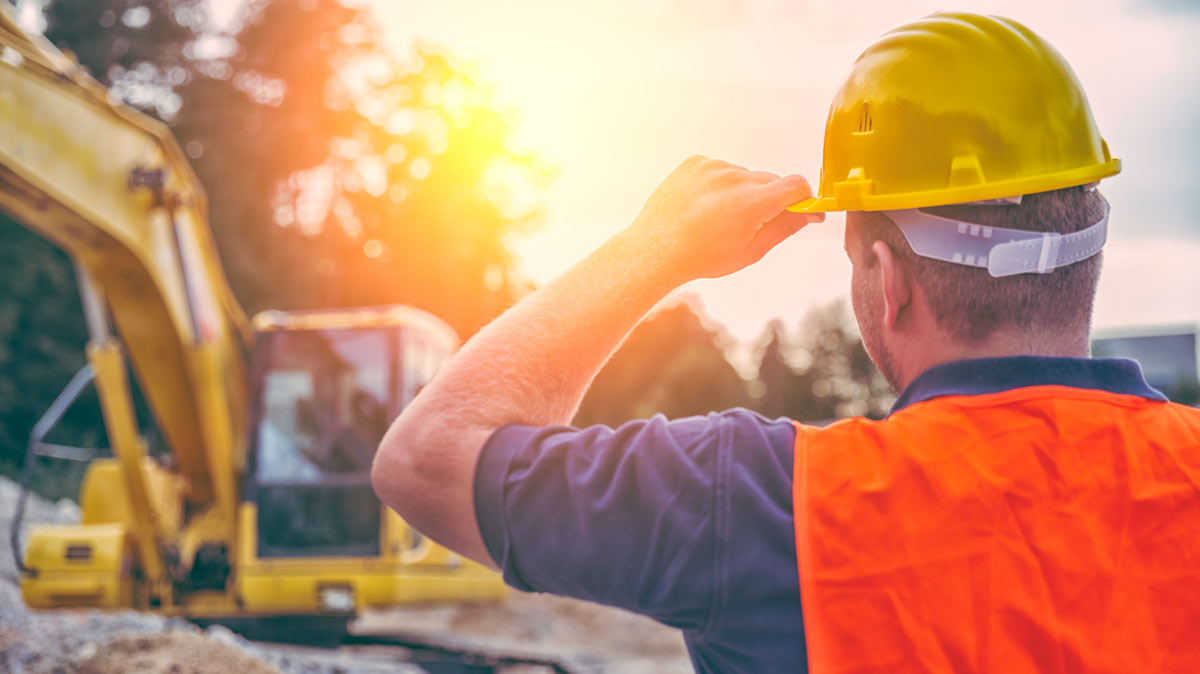 Construction worker surveying job site at sunset