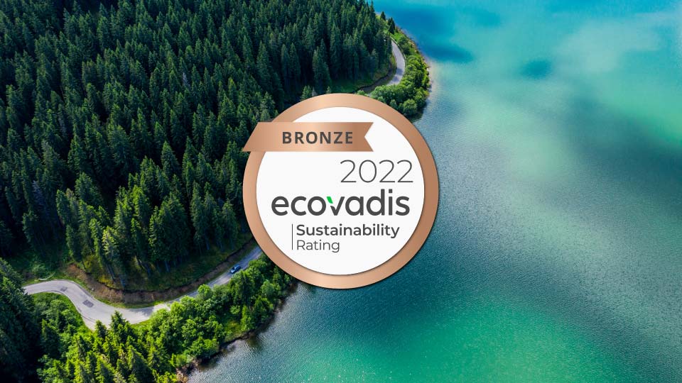Foto de un lago azul con un bosque al lado con el logo de EcoVadis en el centro.