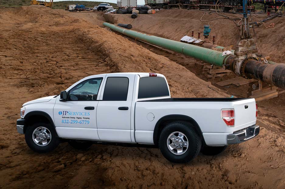 White pickup truck with JPServices logo on it parked beside pipeline 
