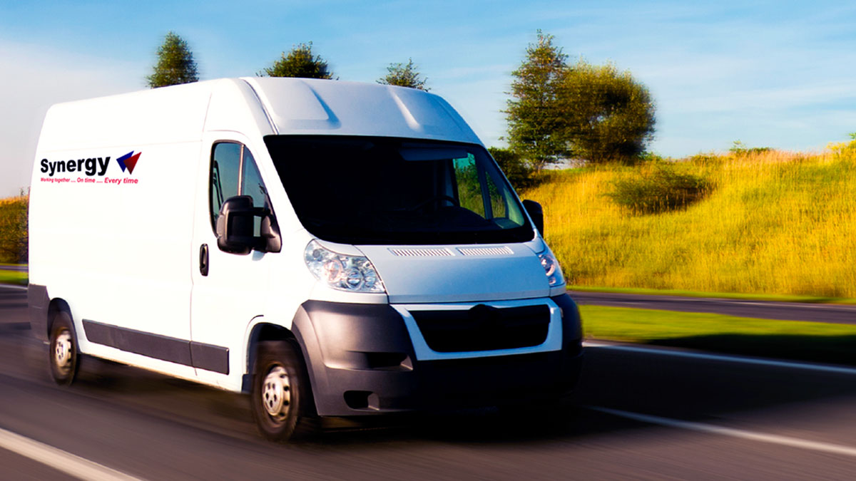White shuttle van driving on open road