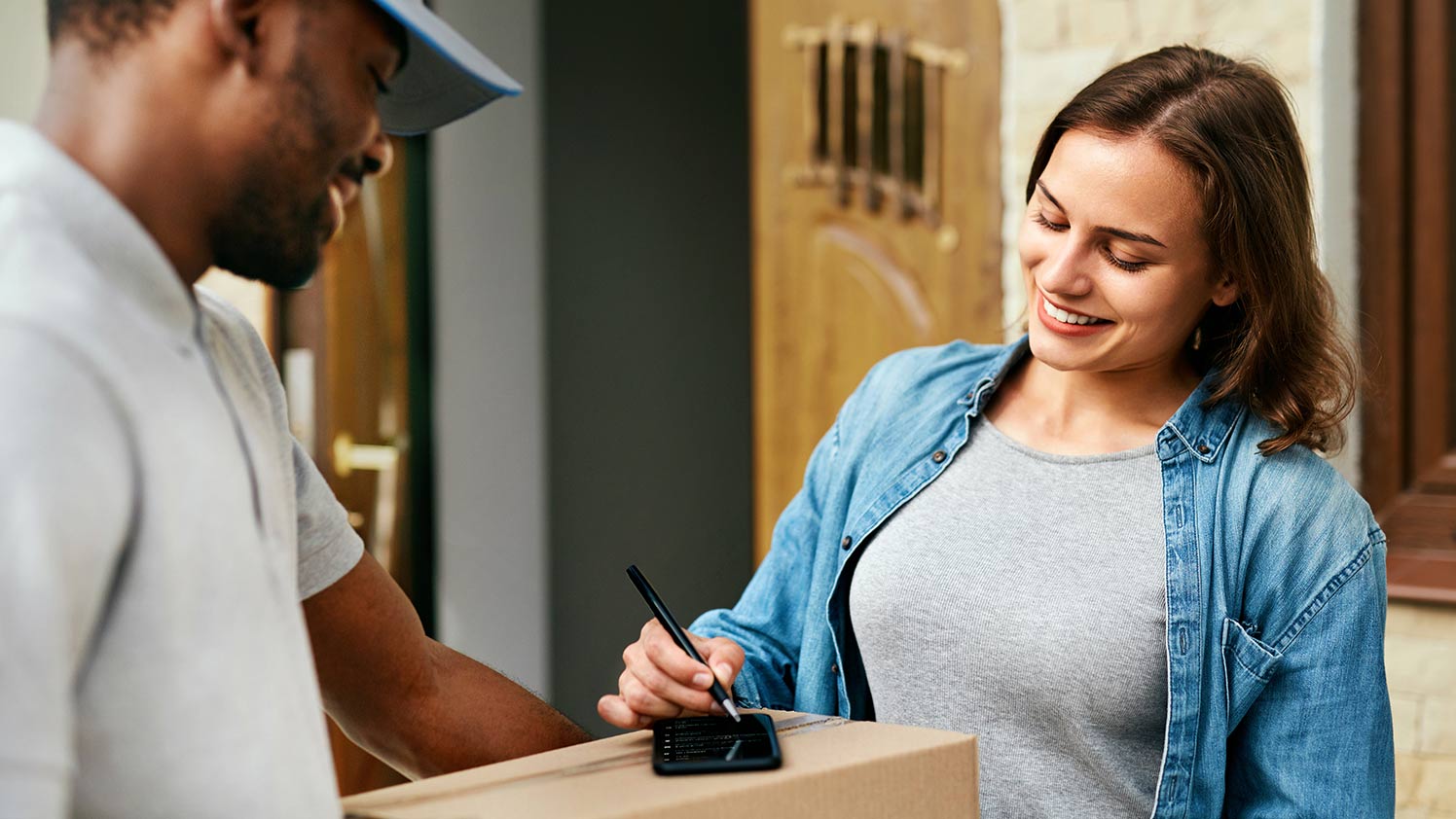 Person signing a delivery outside of their house Person signing a delivery outside of their house