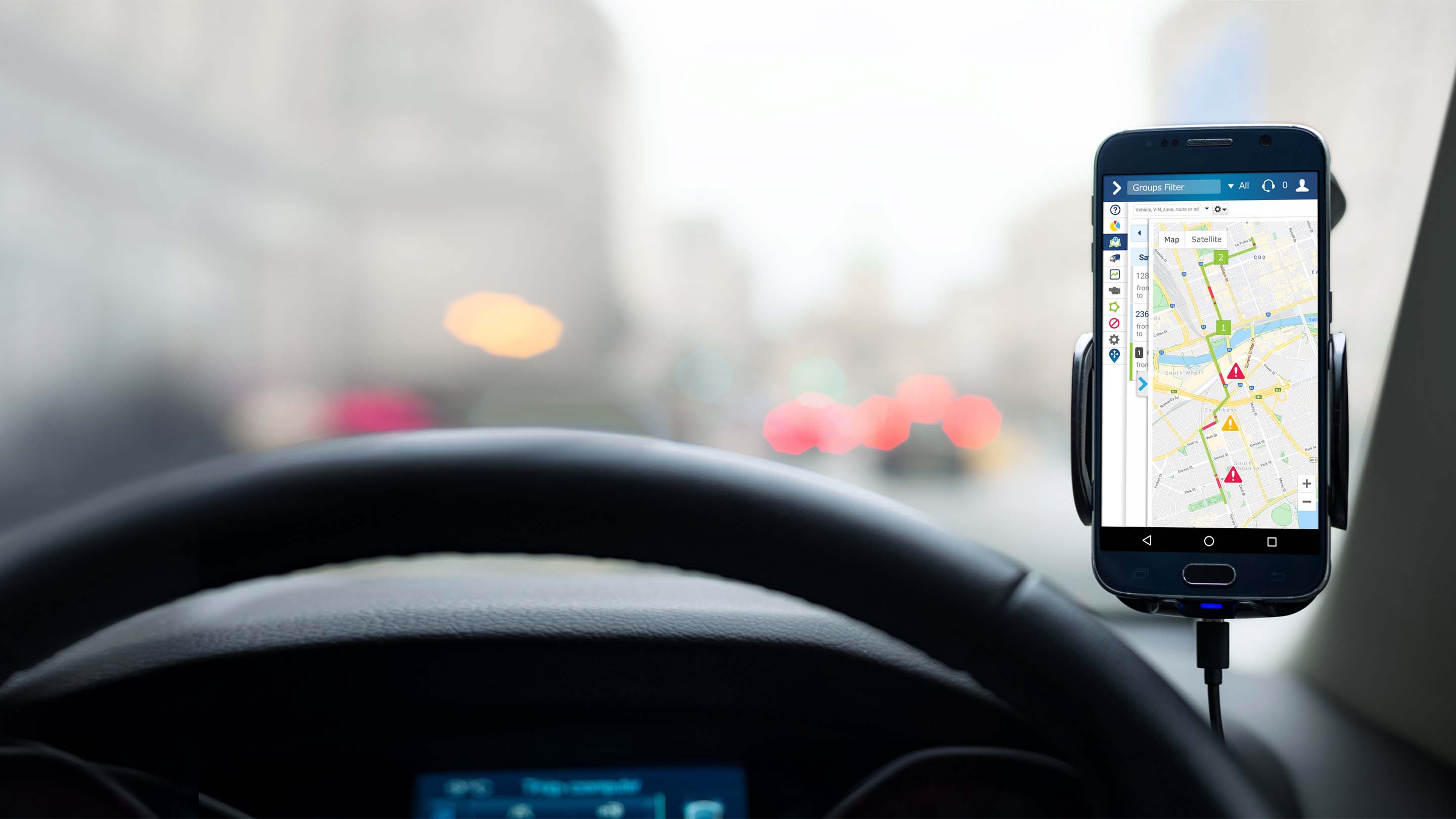 Phone attached to front of car displaying map on MyGeotab app