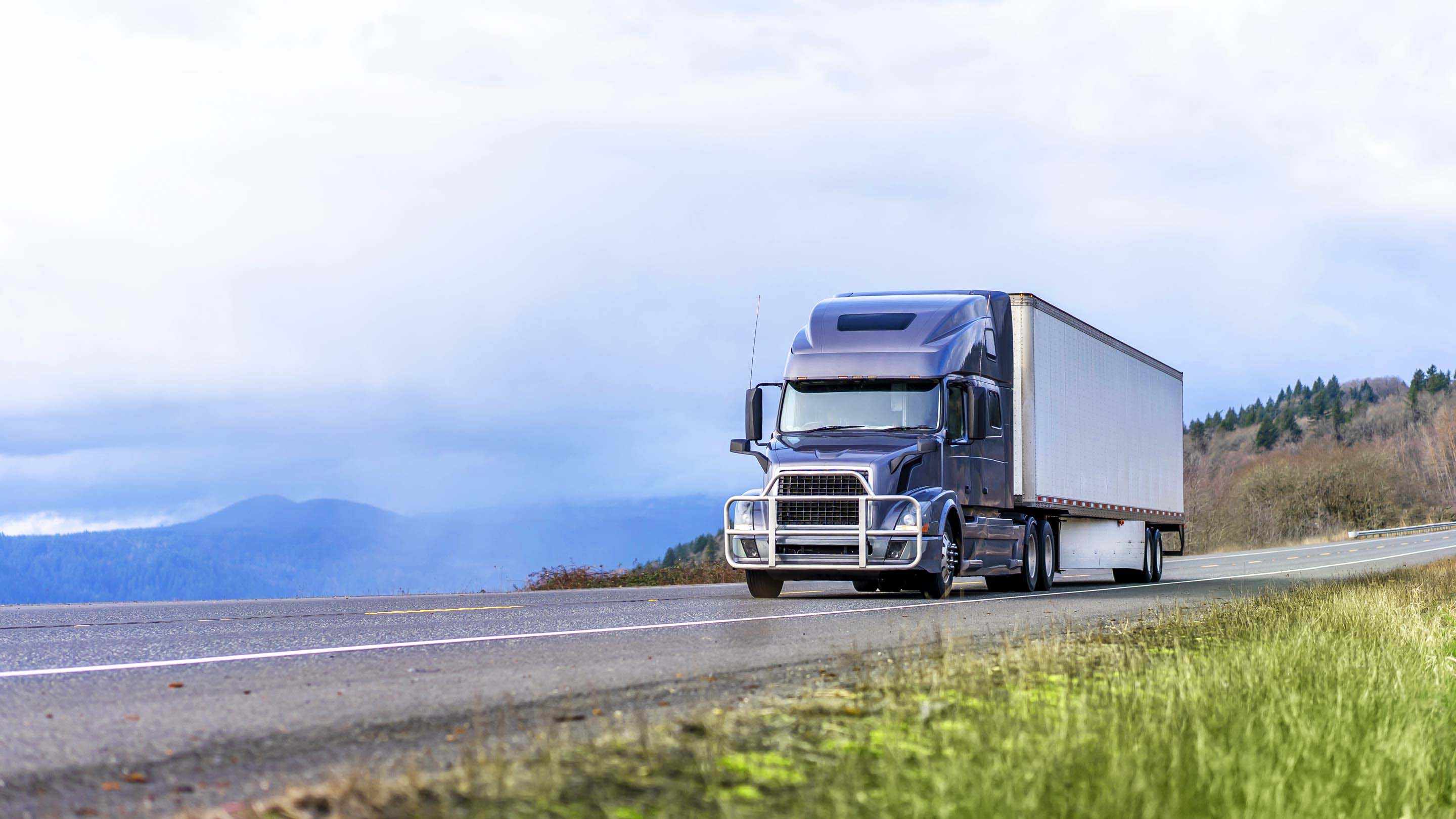 Blue and white truck driving on an open road