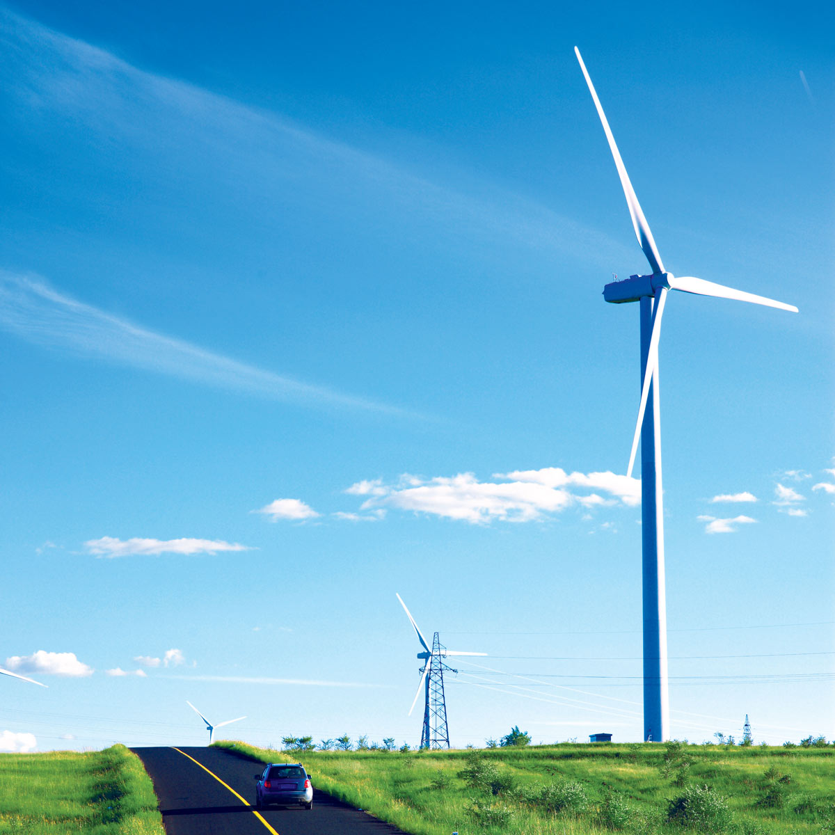 Voiture circulant sur la route avec de grandes éoliennes à côté
