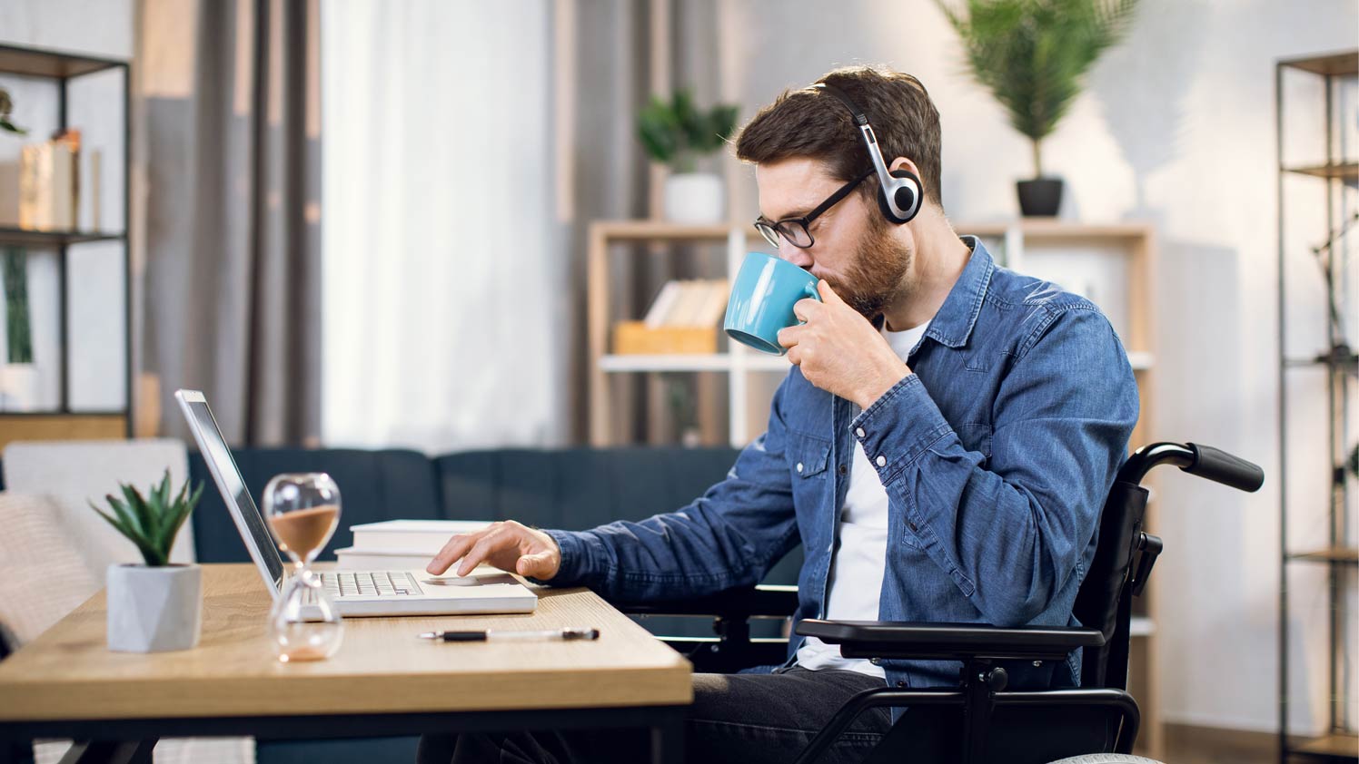 Man using laptop at desk while sipping coffee