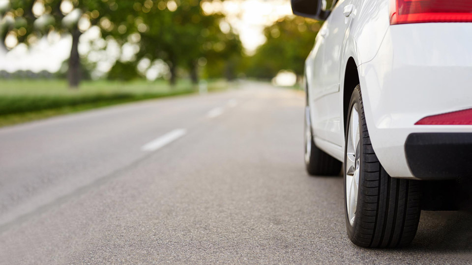 Voiture blanche sur une route près d'un parc