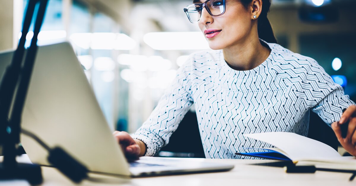 Professionnelle utilisant un ordinateur portable pour consulter des données numériques, illustrant l’utilisation des API dans la gestion de flotte automobile