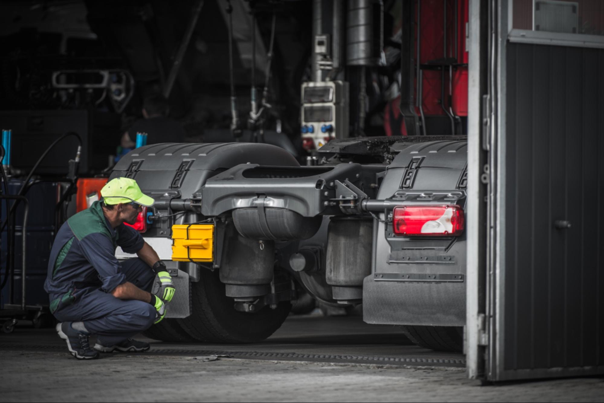 Mécanicien inspectant le châssis et la transmission d'un camion dans un atelier.