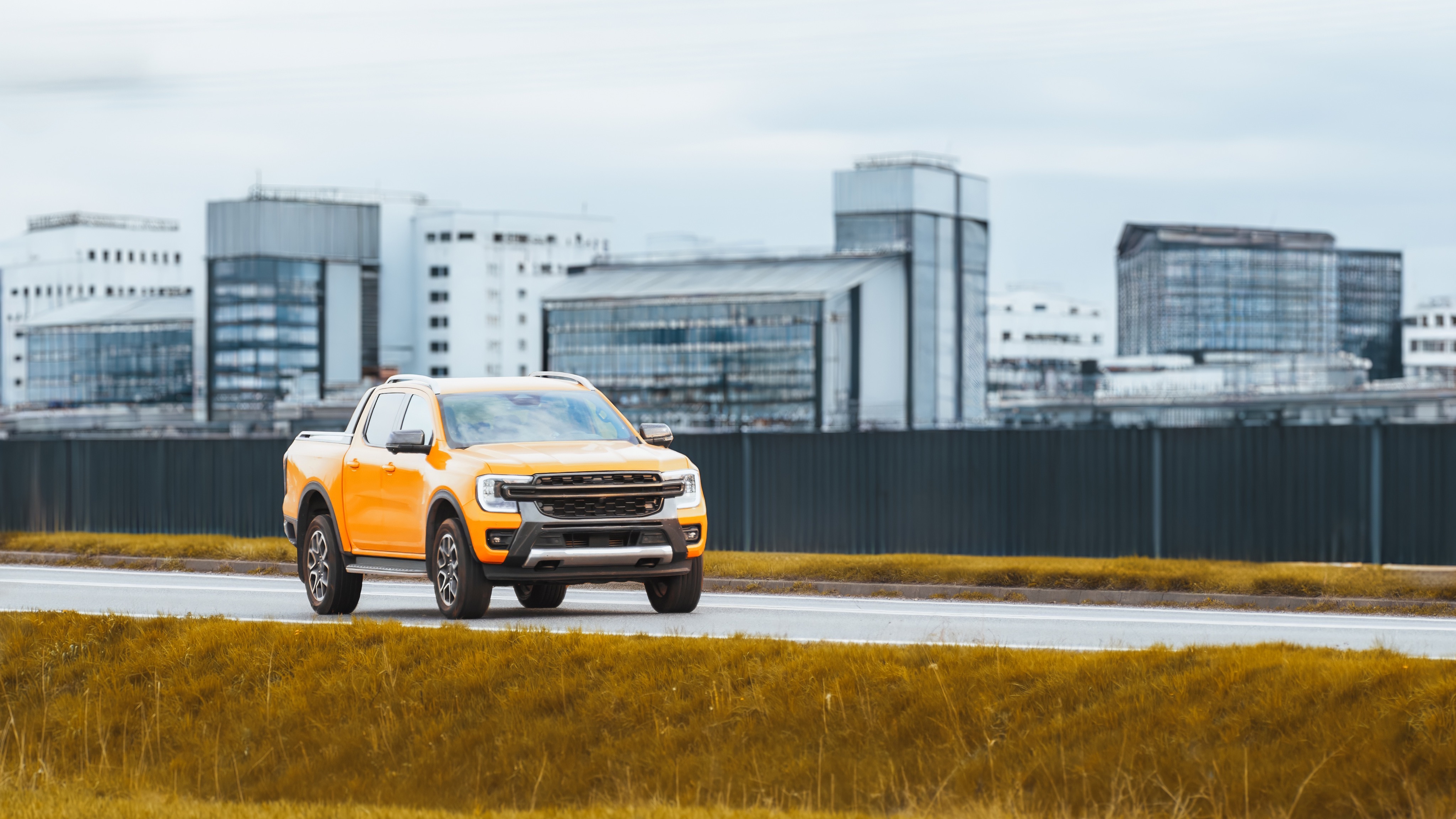 Pick-up orange circulant devant des bâtiments industriels modernes, illustrant les innovations du transport à l’IAA Transportation 2026