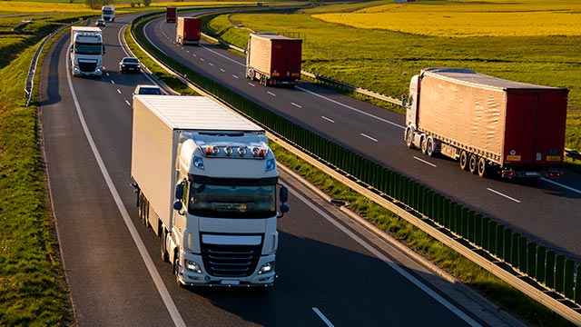 três caminhões em uma rodovia 