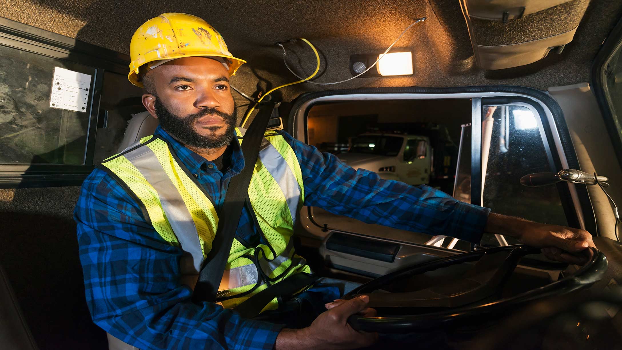 A truck driver wearing his seat belt and driving 