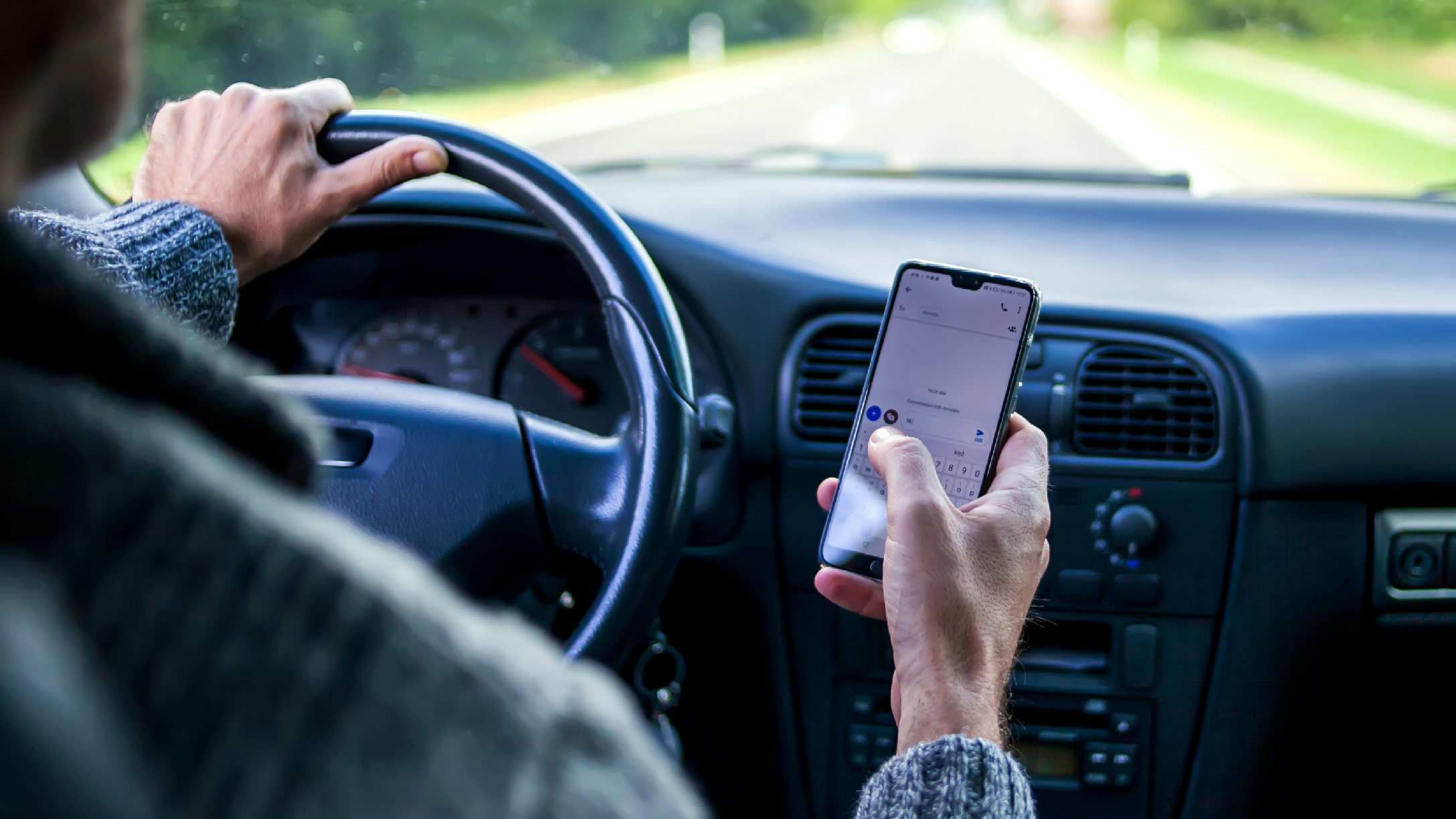 Driver looking at cell phone while driving car 