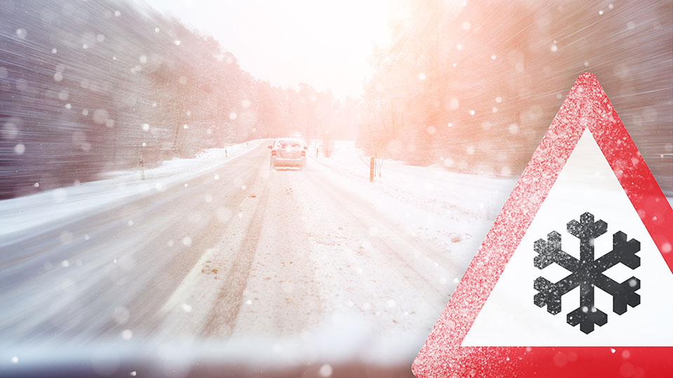 A road with snow and a winter sign