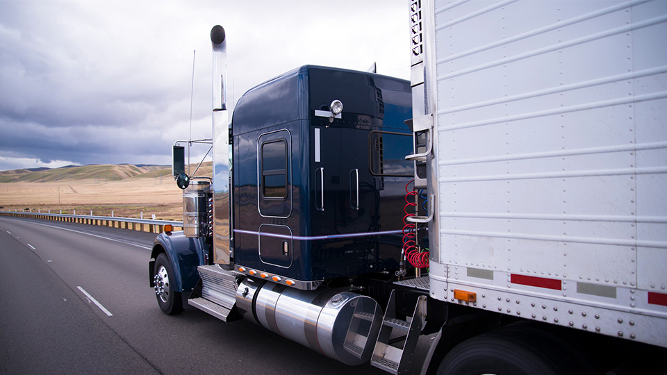 White and blue heavy duty truck on a freeway