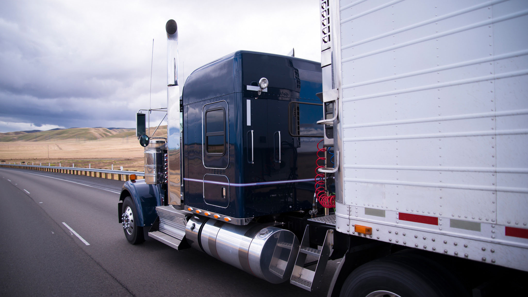 White and blue heavy duty truck on a freeway