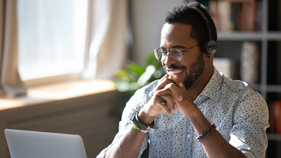 Man smiling in front of a laptop working remotely