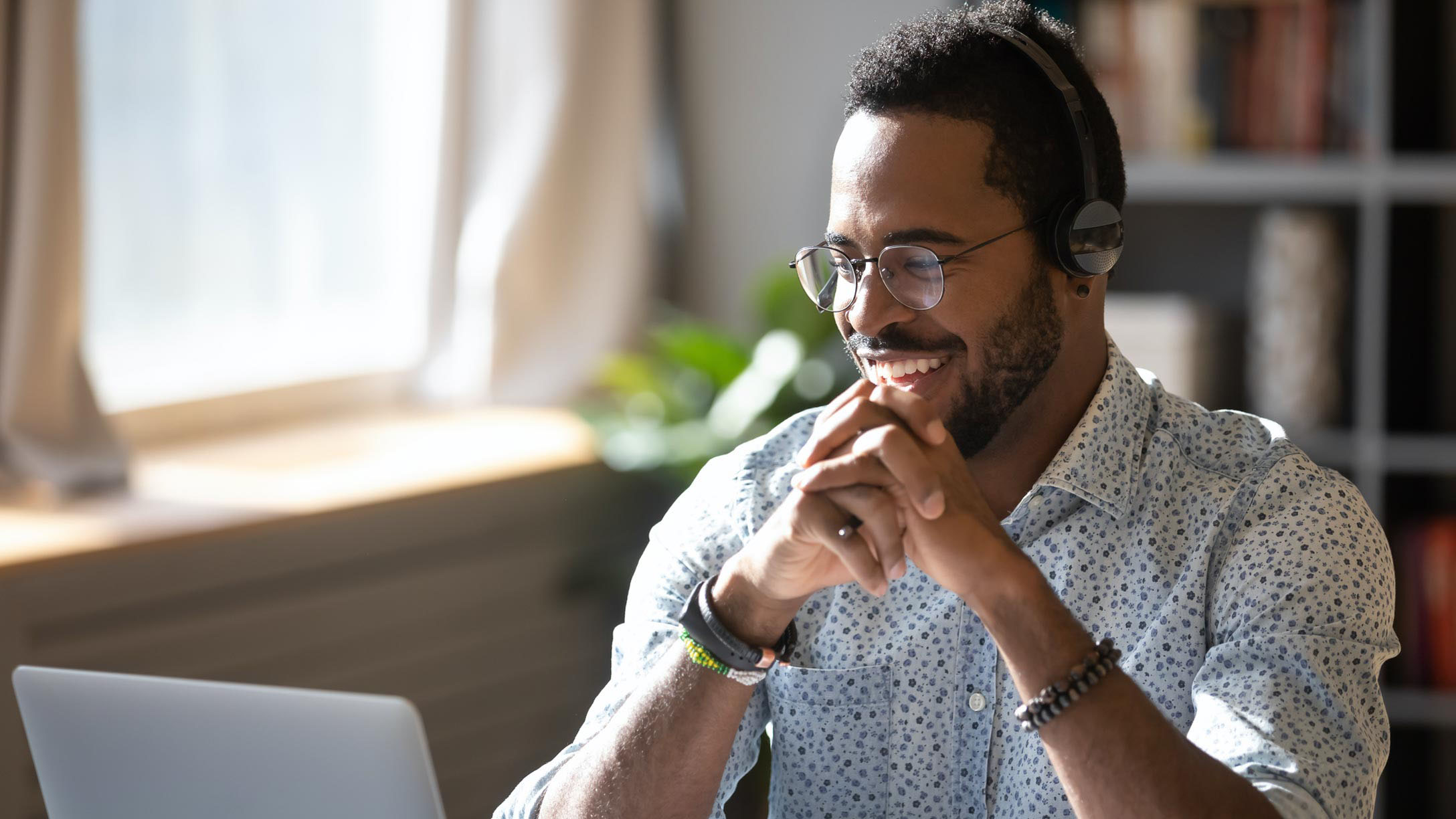 Man smiling in front of a laptop working remotely