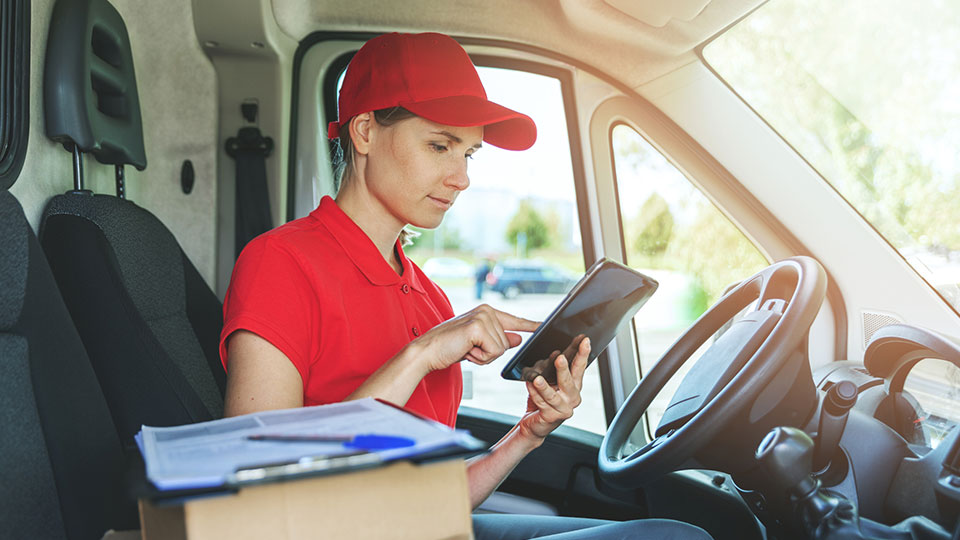 Woman using an ELD in a parked vehicle wearing a red hat