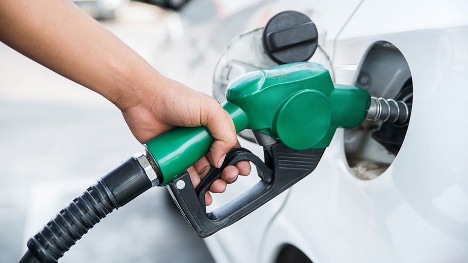 Person holding a fuel nozzle and putting gas in their car