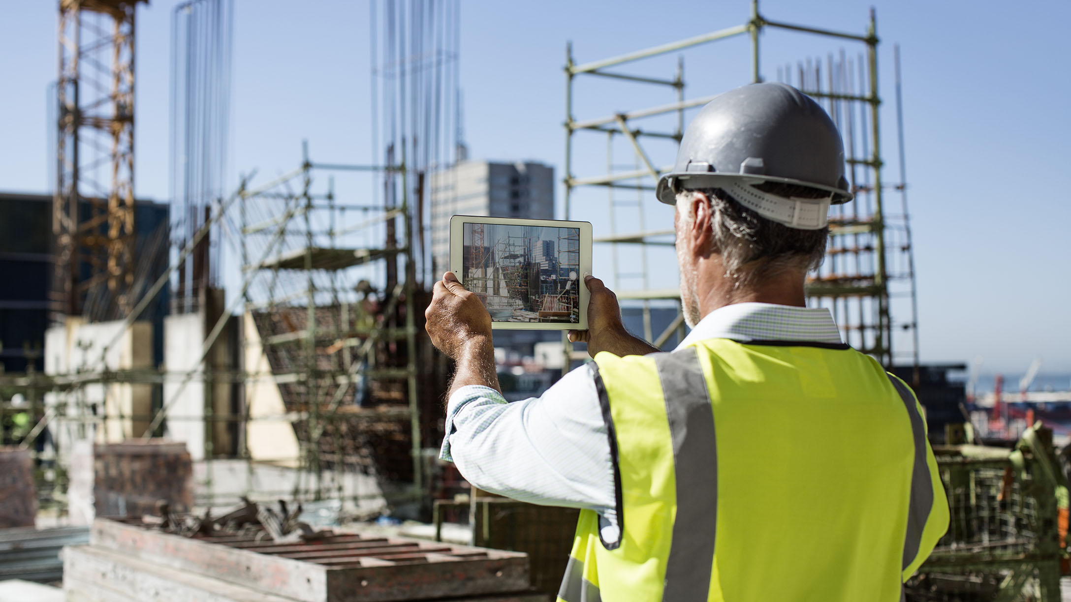 A man at a construction site looking at a tablet screen 