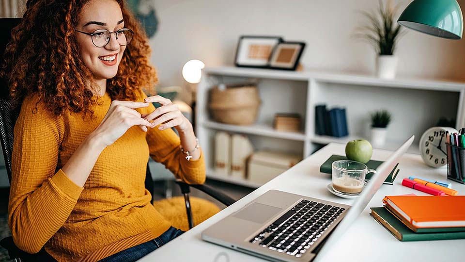 A girl smiling at her computer while working from her home office