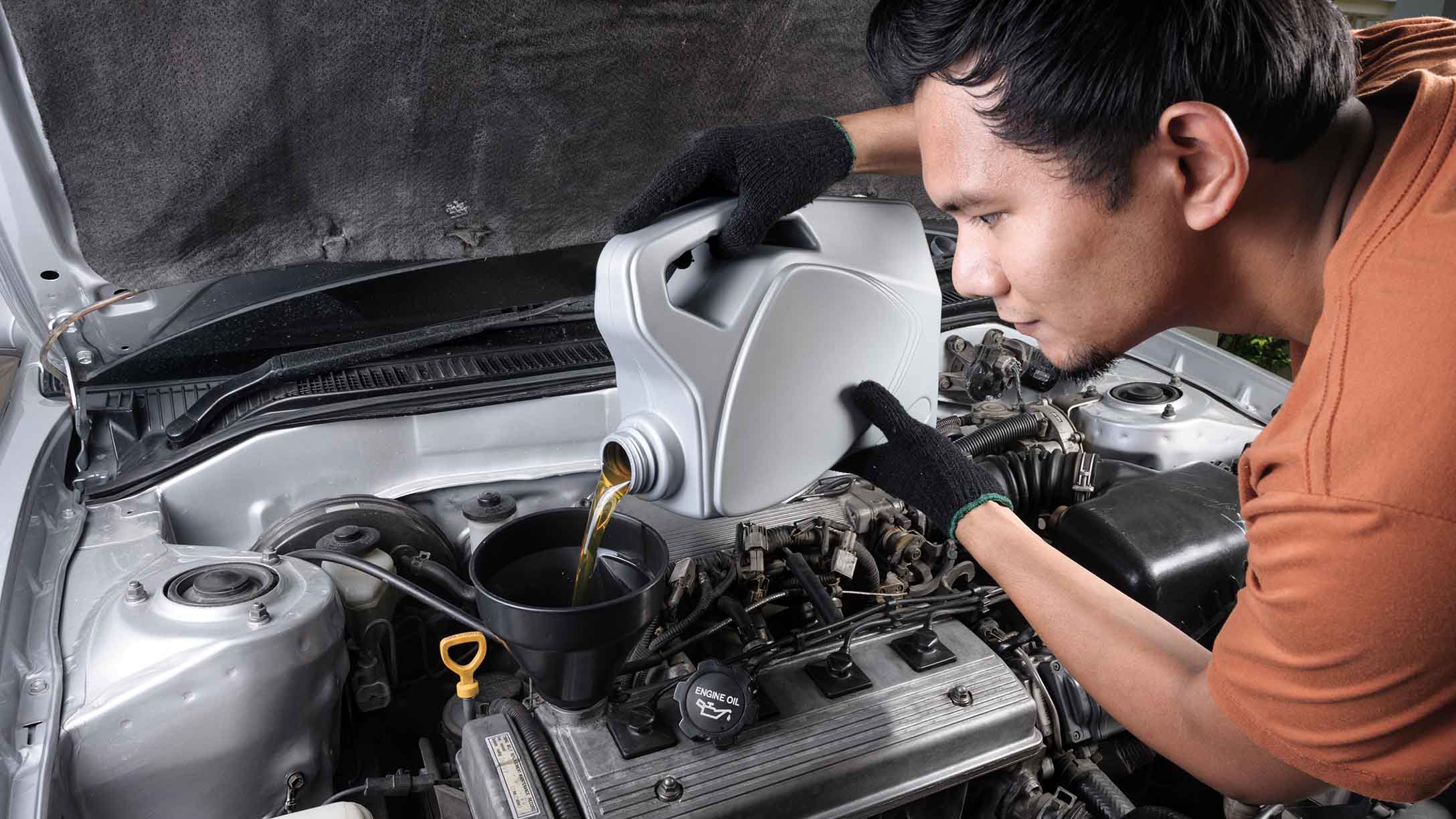 Mechanic pouring engine oil in vehicle