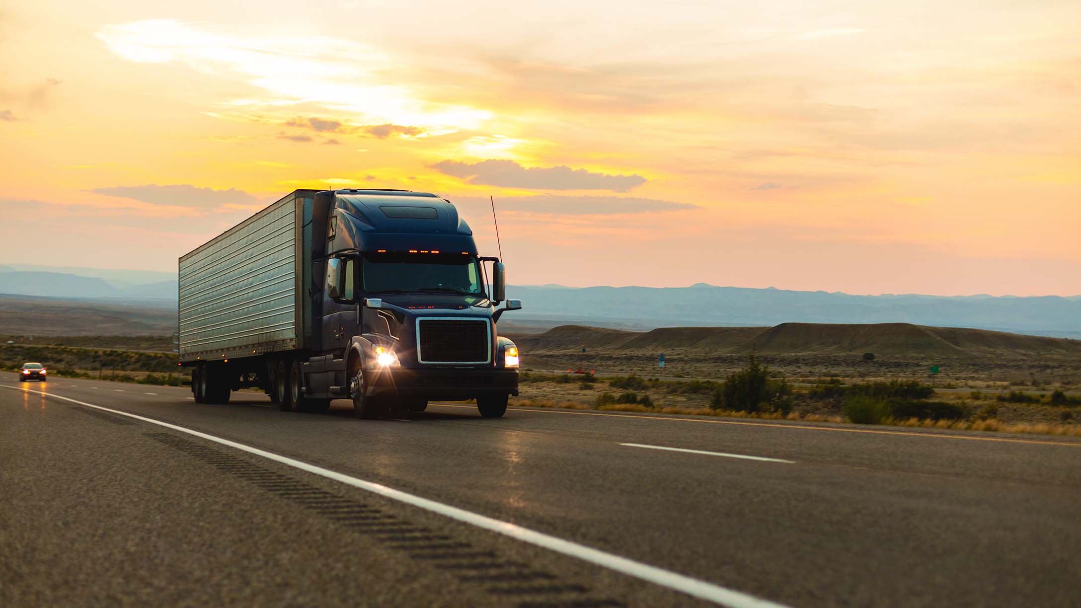 A truck on the highway with a sunset in the back