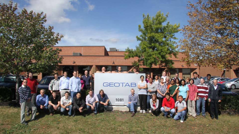 photo of the Geotab team standing next to Geotab sign