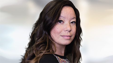 Photo d'une jeune femme aux cheveux bruns souriant par-dessus son épaule